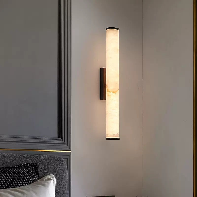 Marble tube aerq wall sconce illuminating a contemporary bedroom with elegant grey wall panelling