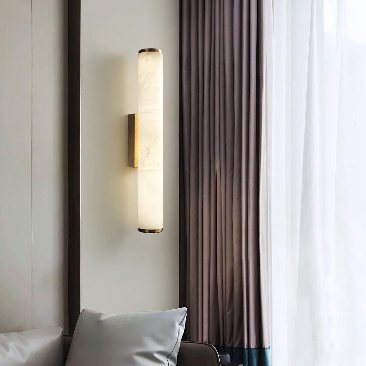 Vertical marble aerq wall lamp providing elegant ambient lighting next to a bright window with curtains