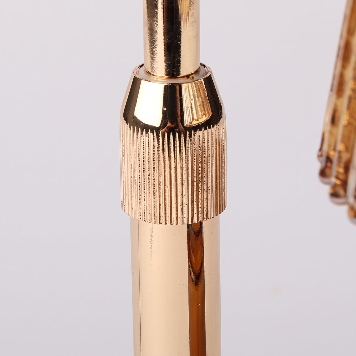 Close-up of the Ambra candle warmer lamp ribbed gold-finish height adjuster collar on a light grey background