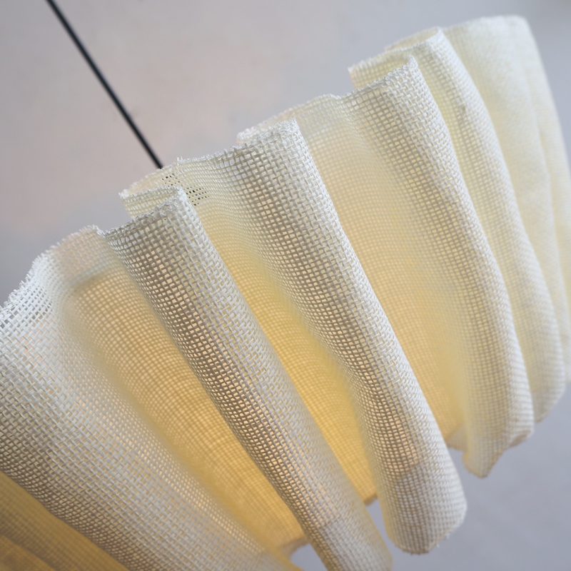 Close-up detail of the illuminated natural pleated fabric aqer lampshade showcasing its organic texture