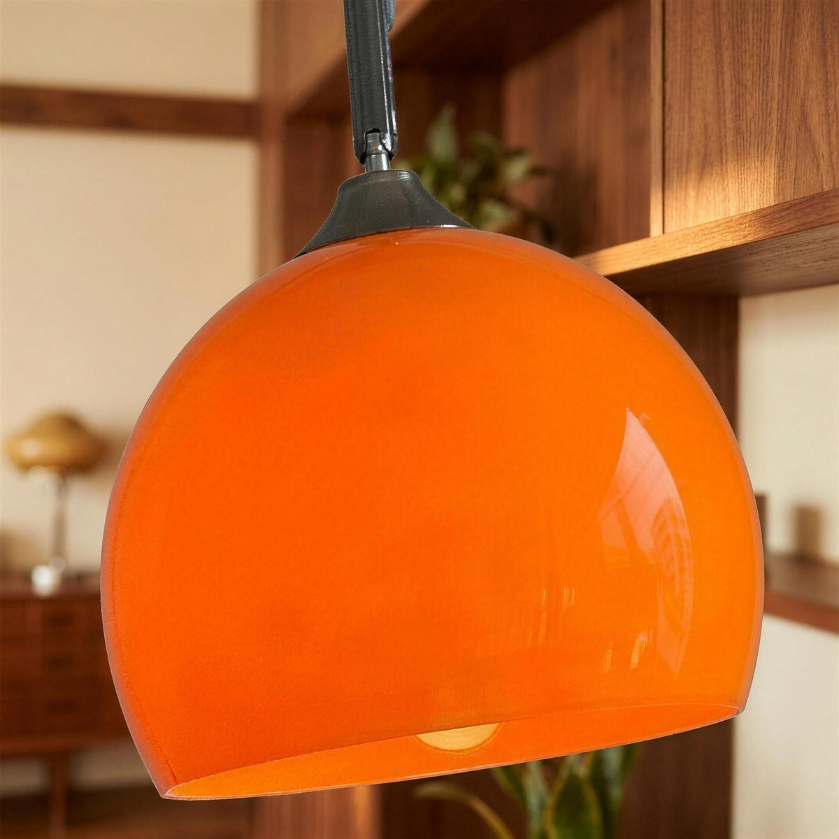 Close-up of the Ardo orange acrylic dome lampshade lit and joined to the steel arm