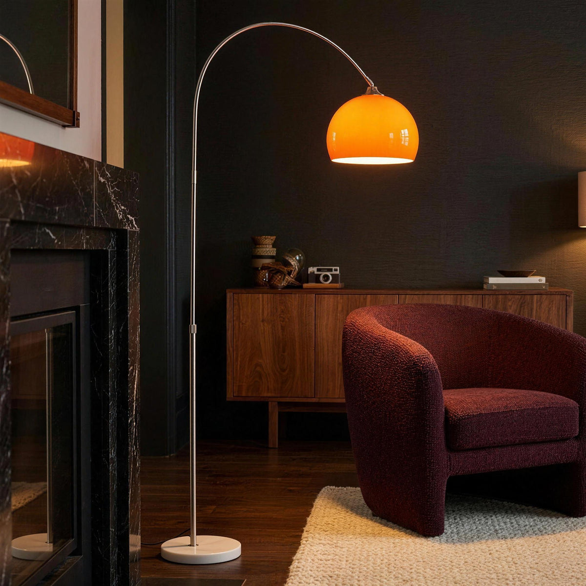Ardo orange arc floor lamp in a living room with a black marble fireplace and a burgundy bouclé chair