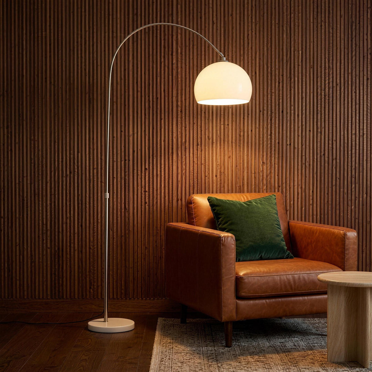 Ardo white arc floor lamp arching over a cognac leather armchair in a lounge with fluted wall panelling