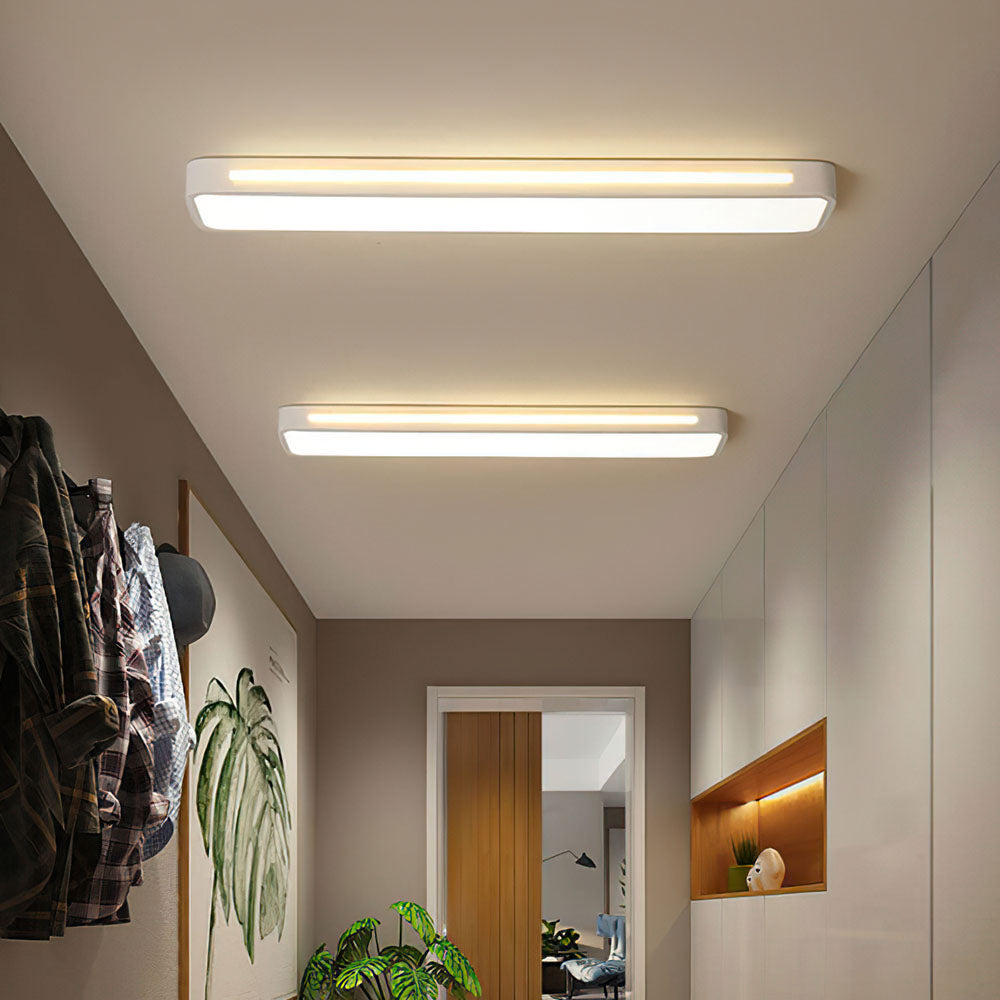 Two modern white linear flush mount atio ceiling lights installed in a bright minimalist hallway