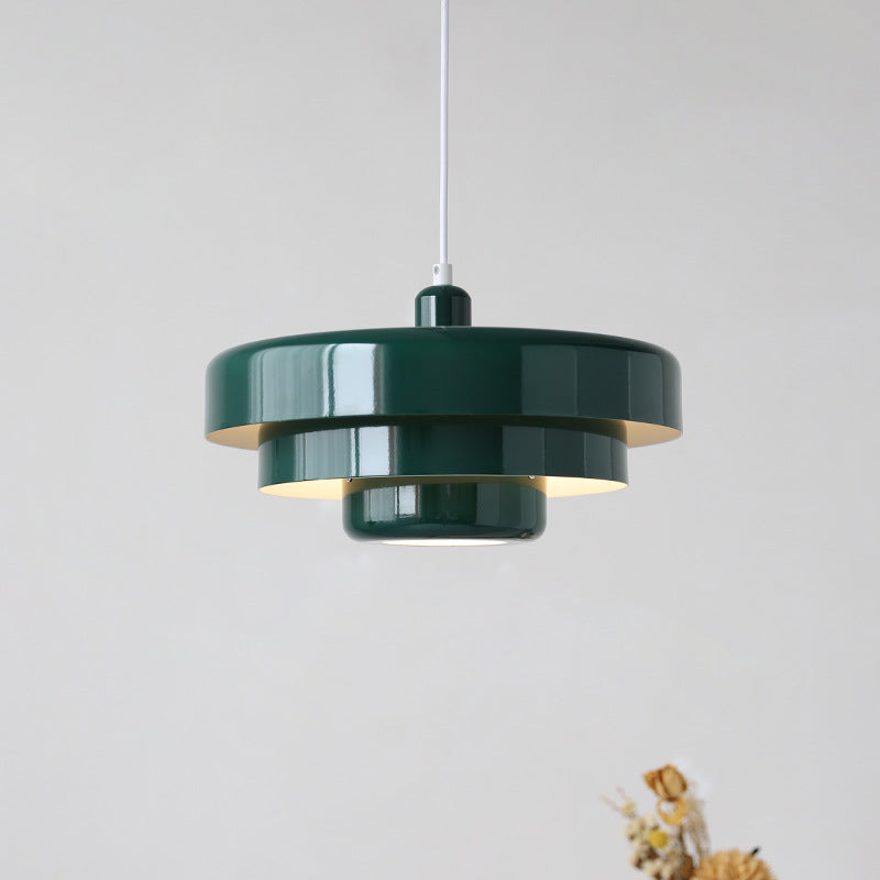 Sleek dark green balel mid-century Bauhaus tiered pendant lamp isolated on a light neutral background