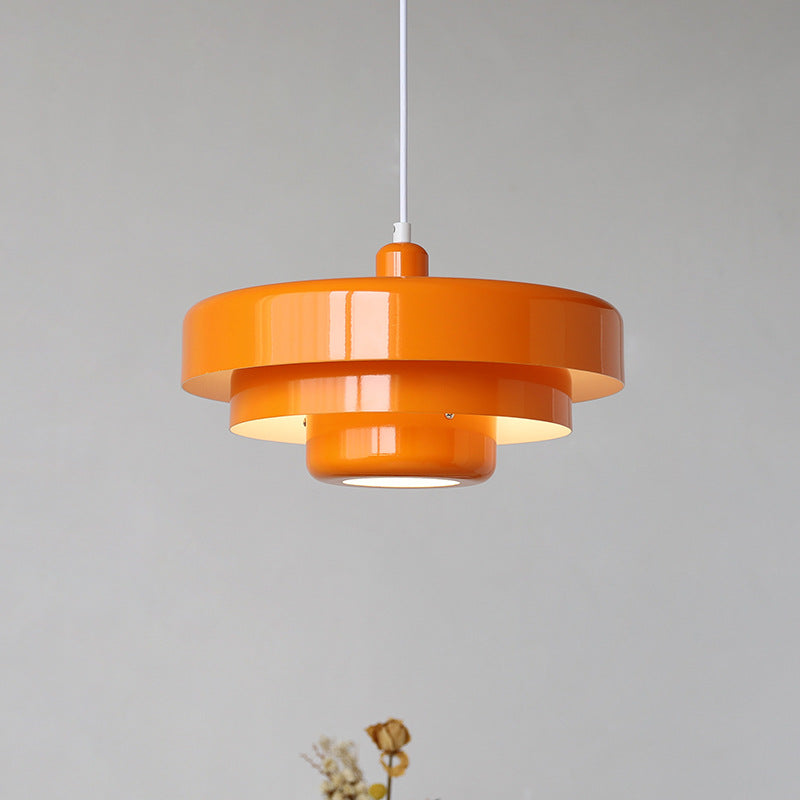 Bright orange mid-century modern layered balel pendant lamp isolated against a light grey background