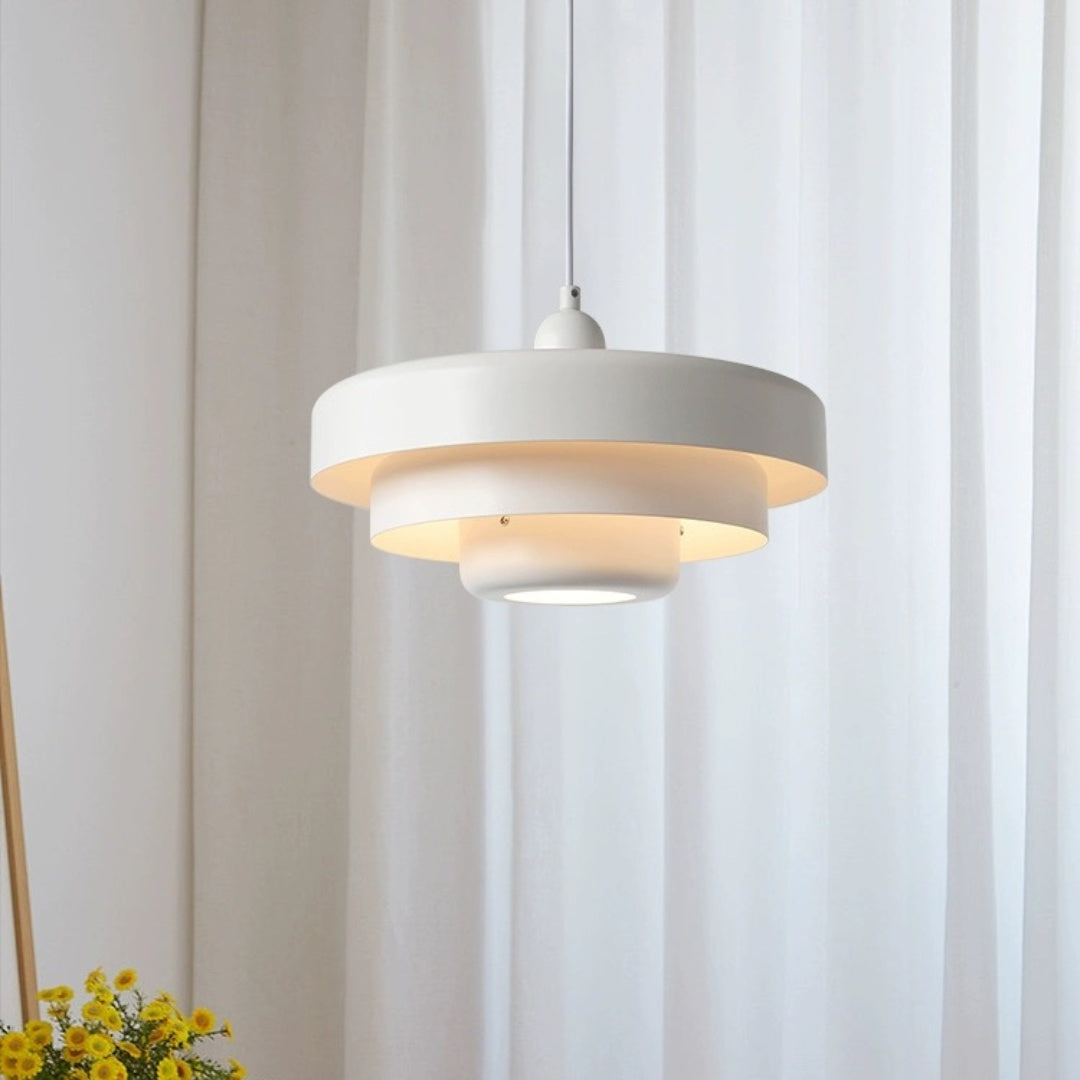 Single white layered metal balel pendant light suspended in a bright, minimalist reading nook