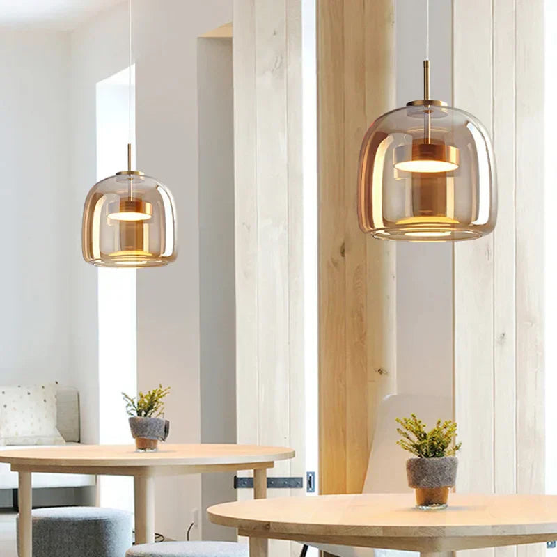 Two warm beqi amber glass pendant lamps suspended over a light wood dining table