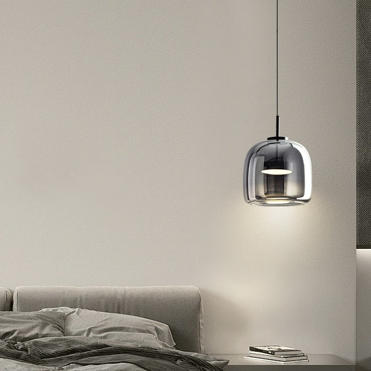 Smoke grey glass beqi pendant light casting a soft, moody glow next to a modern bed