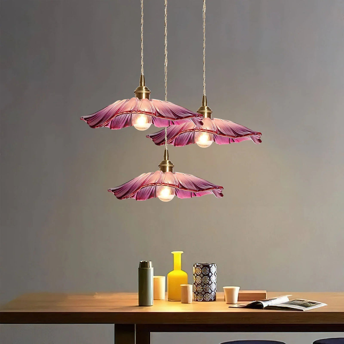 Cluster of three purple retro glass bila pendant lamps hanging over a wooden table