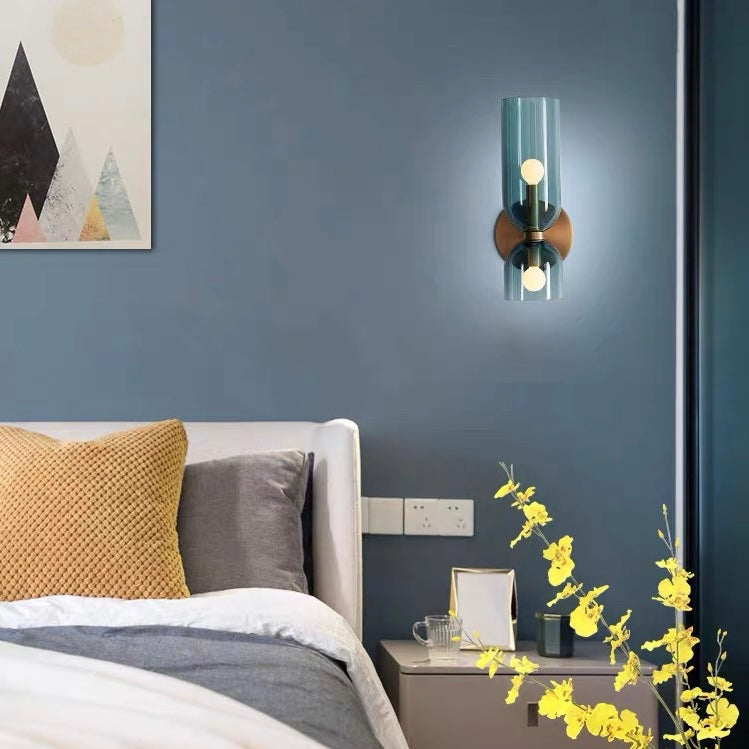 Blue bitlat mid-century modern glass wall sconce installed above a bedside table in a moody blue bedroom