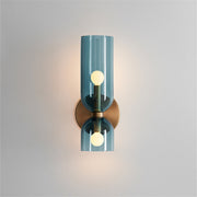 Modern bitlat blue tinted glass hourglass wall sconce providing up and down lighting against a light wall