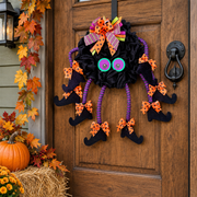 Close-up of Bramblewit witch spider legs wreath with googly eyes on a rustic wooden front door