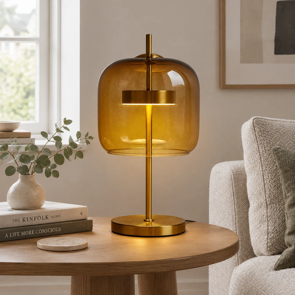 Brolt Amber glass table lamp with gold-finish iron base on a wood table in a modern British minimalist living room, lit