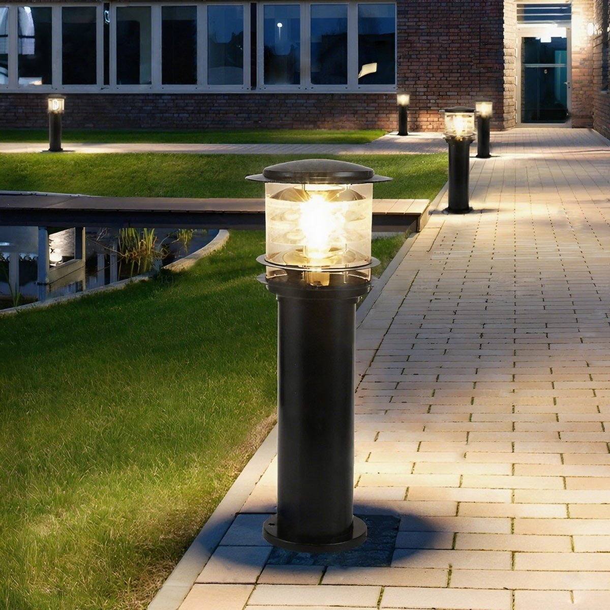 bulba tall black LED path light standing elegantly between a paved walkway and a green lawn
