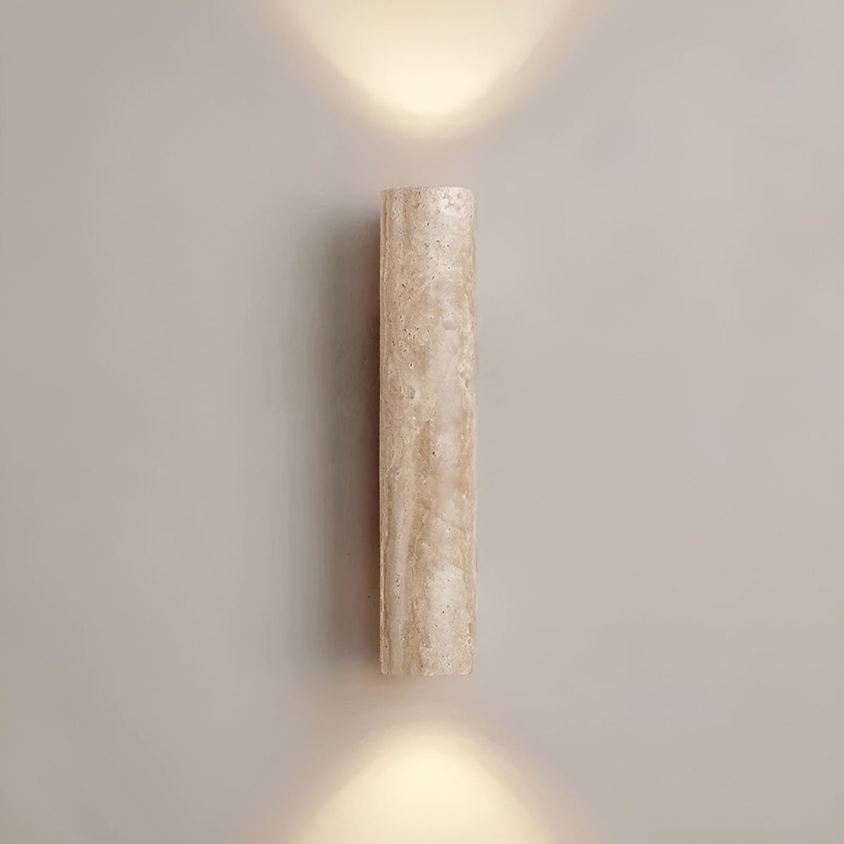 Front view of the beige travertine cylindrical bura wall lamp providing elegant architectural lighting