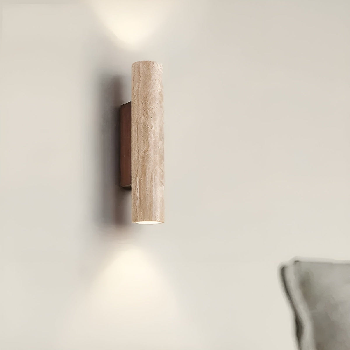 Travertine bura wall sconce mounted next to a grey sofa