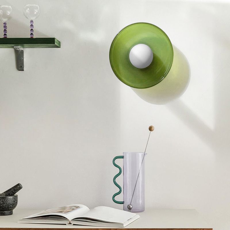 Green glass cenas wall sconce mounted above a minimalist desk and decor