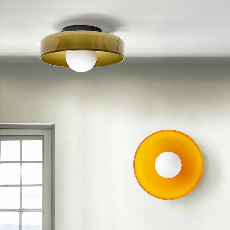 Vibrant orange and olive green glass cenas wall sconce casting a warm ambient glow in a contemporary hallway