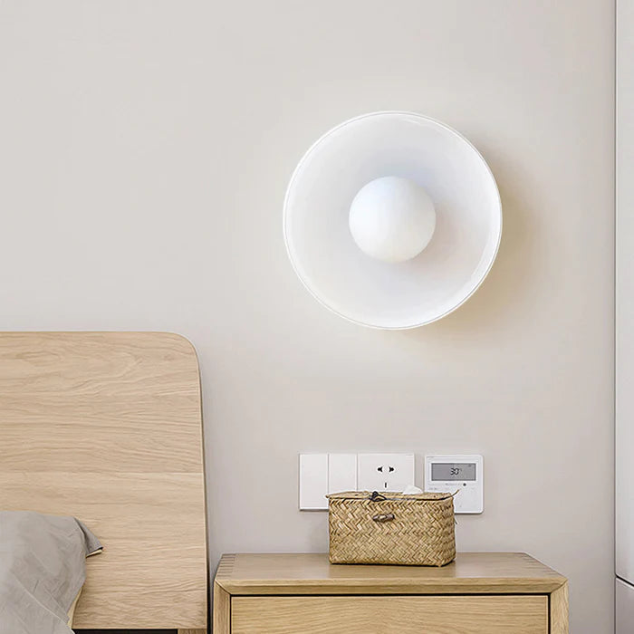 White glass cenas wall sconce acting as an elegant bedside reading light