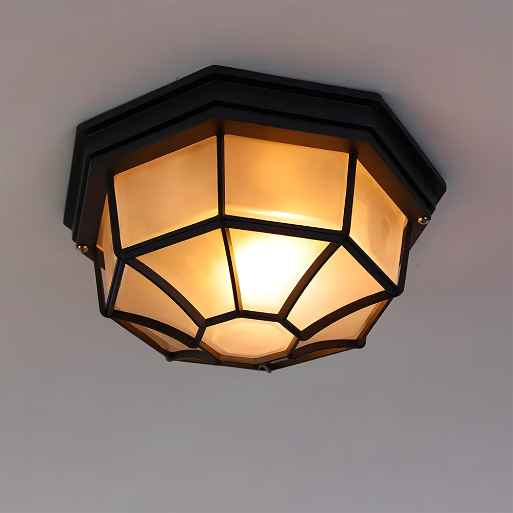 Close-up of an illuminated black rustic cila bulkhead lamp featuring a protective metal cage and frosted glass