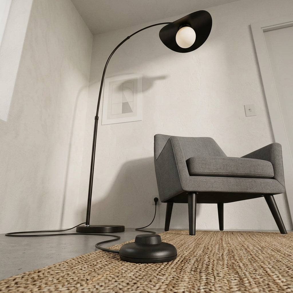 Clent black arc floor lamp with its round base and cable beside a grey armchair on a jute rug