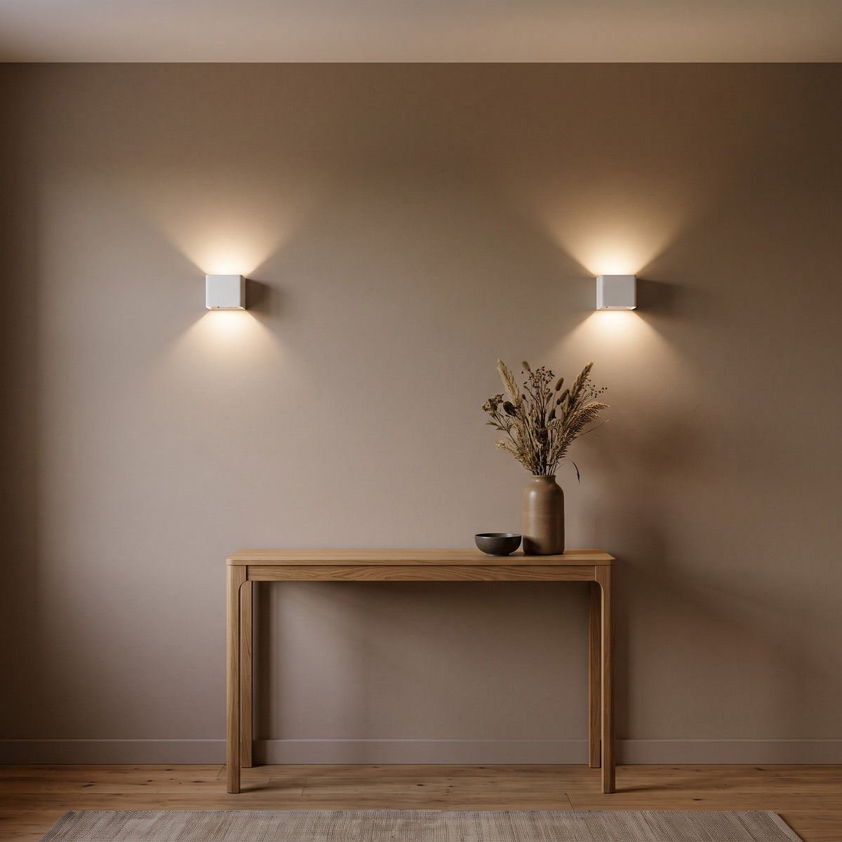 2 Cubo white cube wall lights on a taupe hallway wall above an oak console table with a vase of dried stems