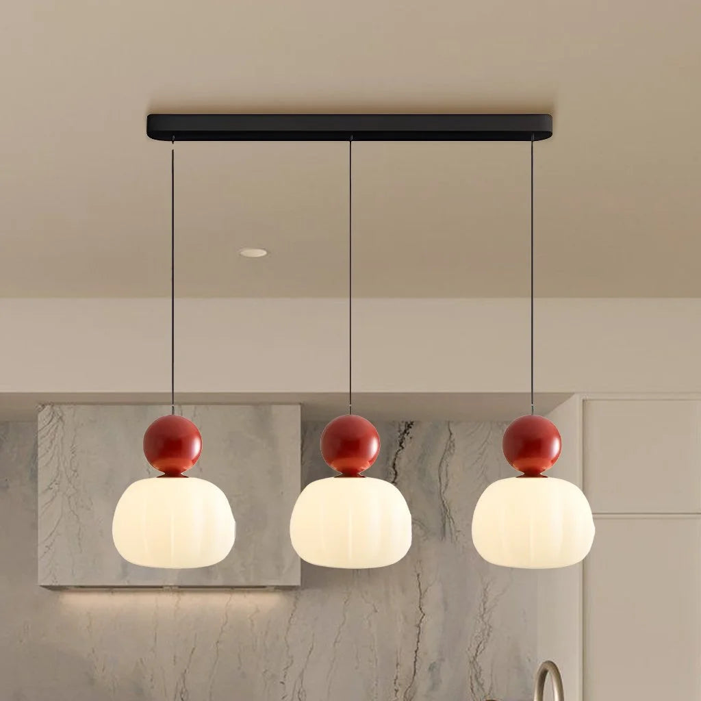 Red three-head debz linear kitchen island lighting adding a vibrant contrast to a neutral kitchen