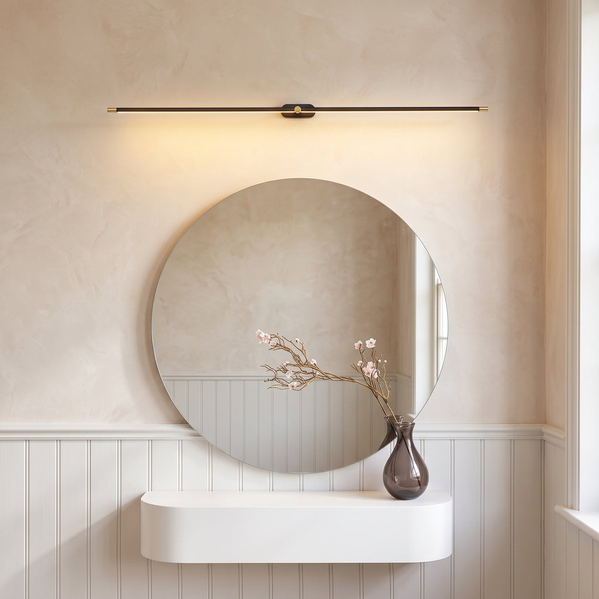 Doven black linear LED wall light above a round mirror and floating white shelf in a British hallway