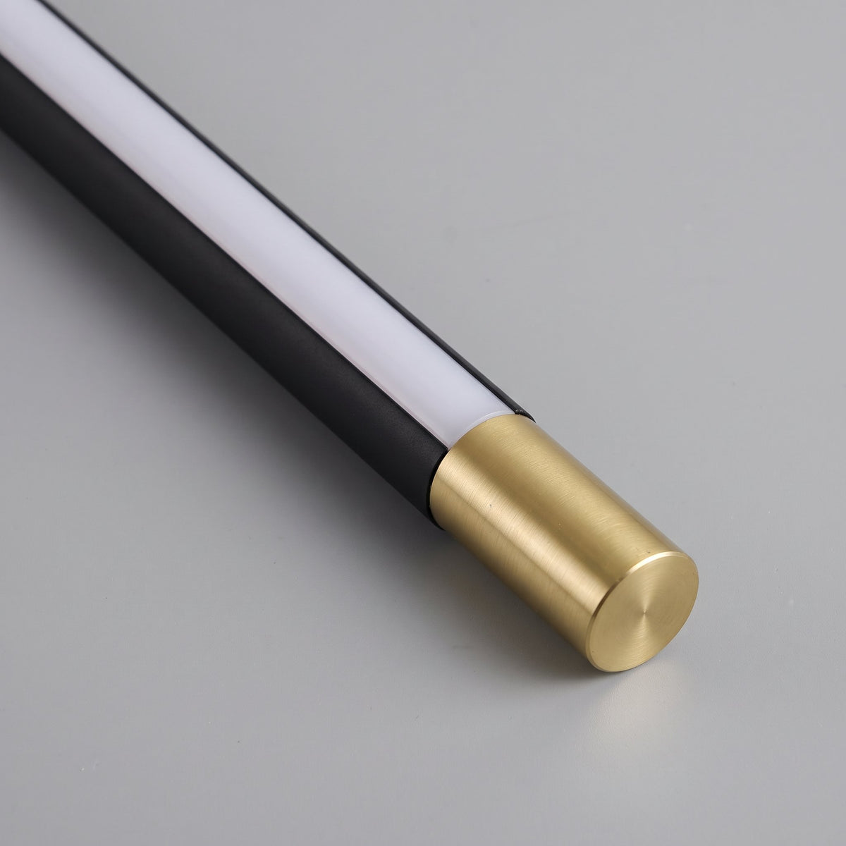 Close-up of the Doven black body with gold-finish end cap and white acrylic diffuser on a studio grey background