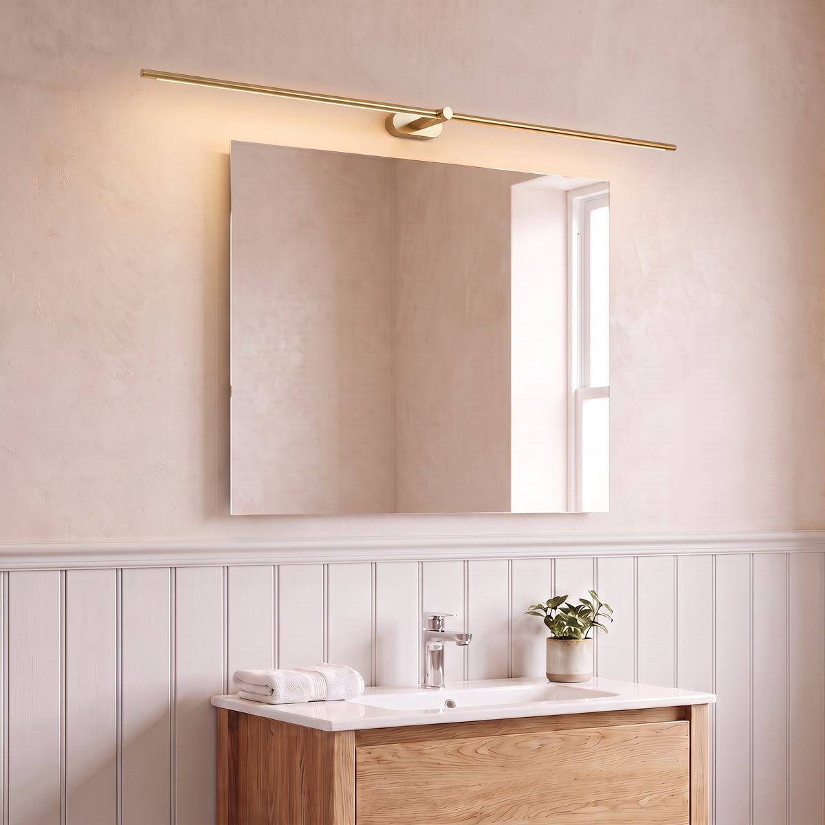Doven gold-finish 98 cm linear LED wall light above a square mirror and oak console in a British bathroom