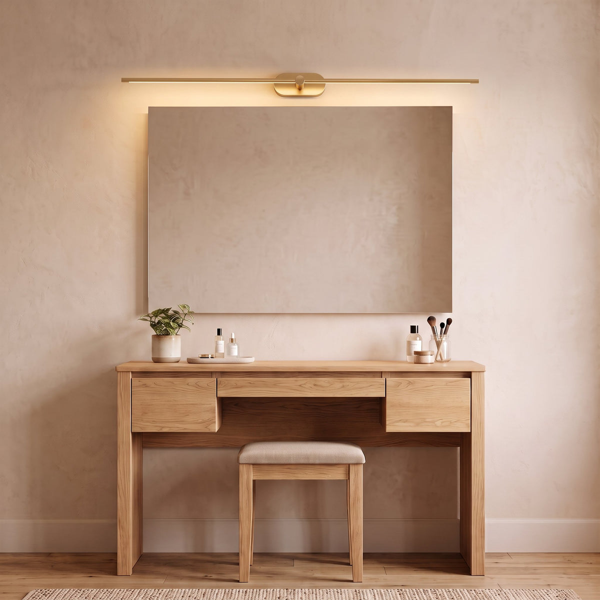 Doven gold-finish linear LED wall light above a wide mirror and oak dressing table with a stool