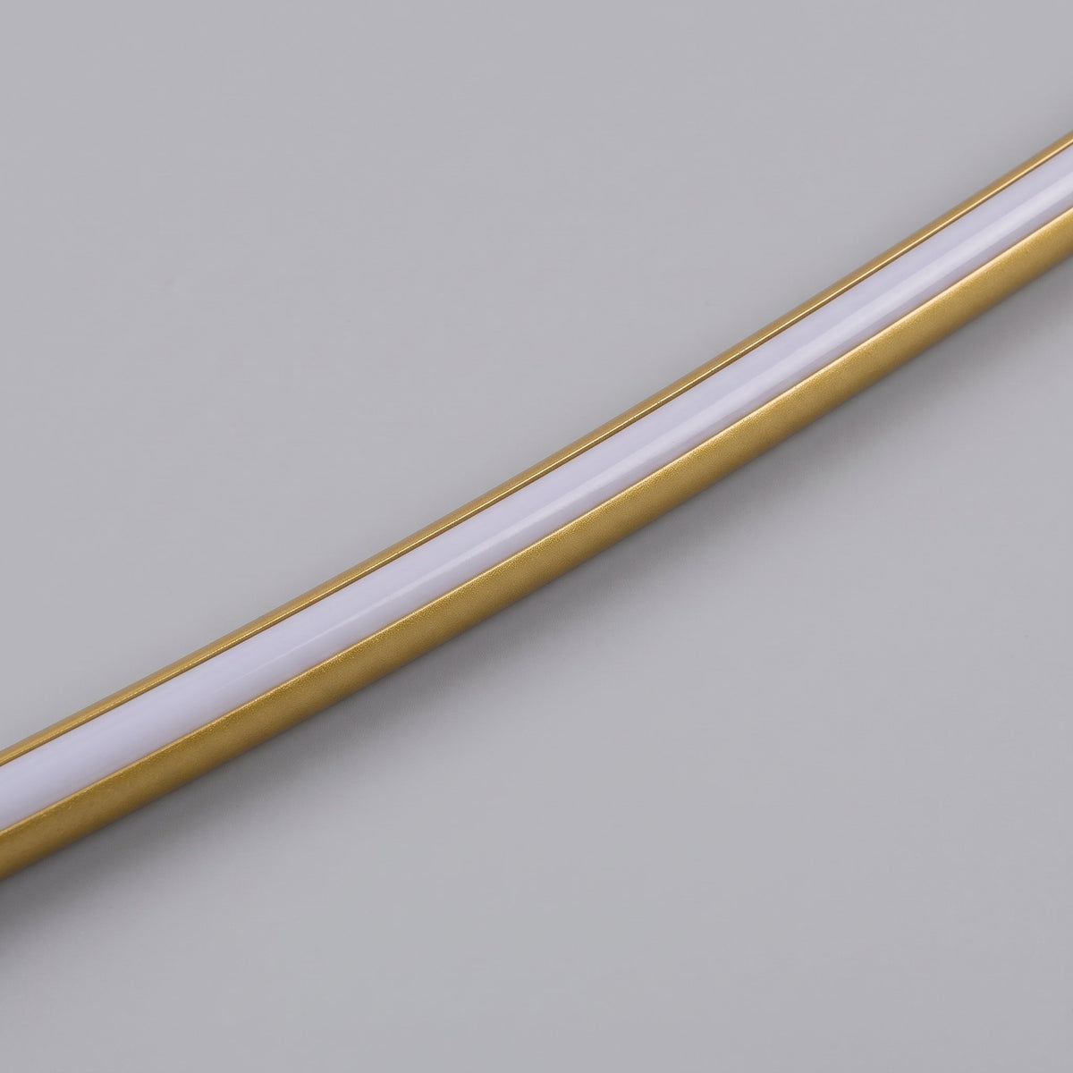 Close-up of the Doven gold-finish tube and white acrylic diffuser on a studio grey background