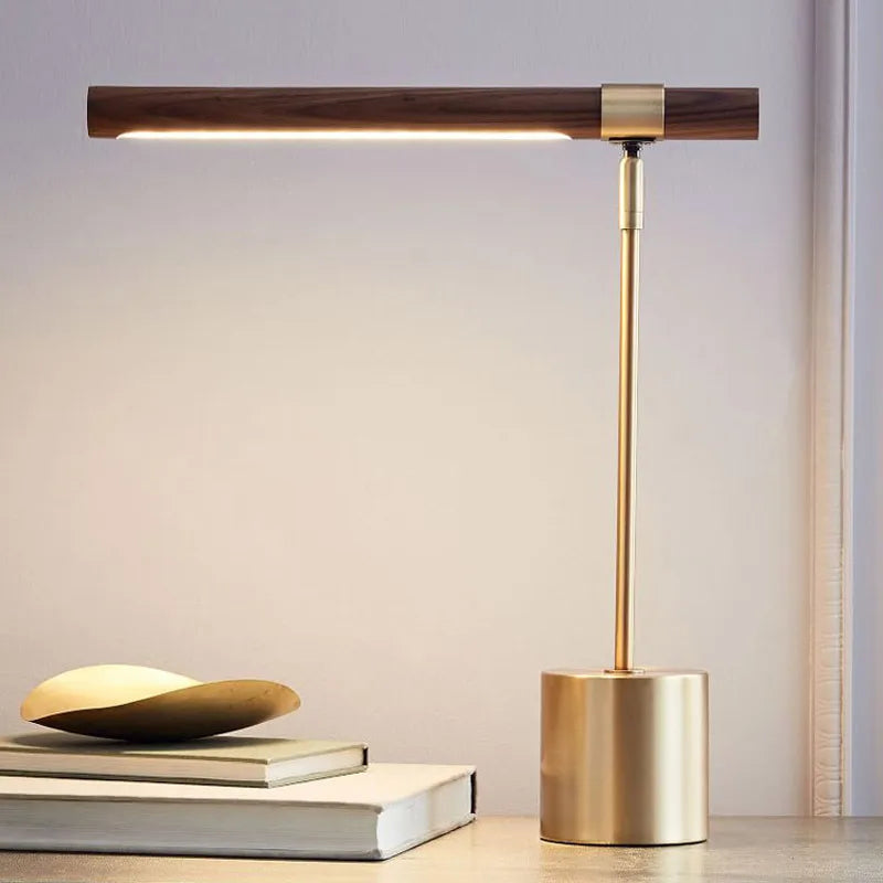 Elkon walnut and brass desk lamp beside a stack of books on a grey studio background