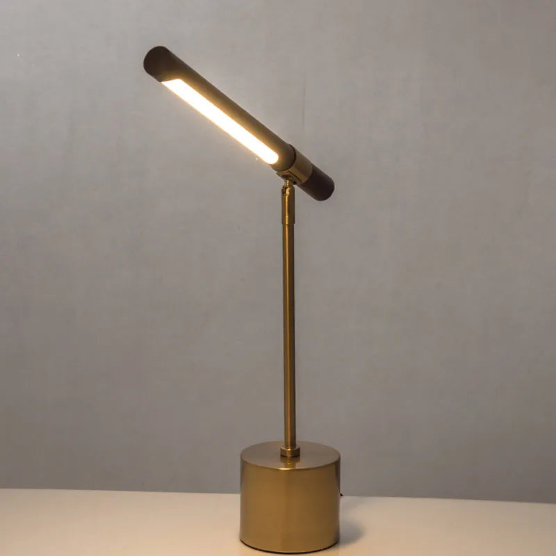 Elkon walnut and brass desk lamp with the head tilted upwards on a grey studio background
