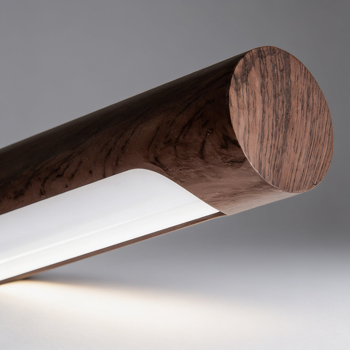Close-up of the Elkon walnut wood light bar with its LED strip on a studio grey background