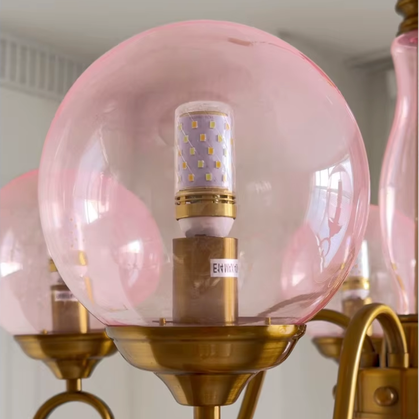Elur chandelier Blush Pink hand-blown glass globe with LED bulb on brass-finish iron arm cup, close-up