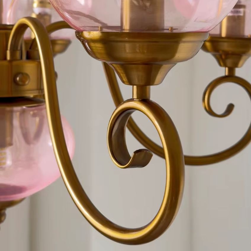 Elur chandelier hand-aged brass-finish iron scrolled arm, close-up with Blush Pink globes
