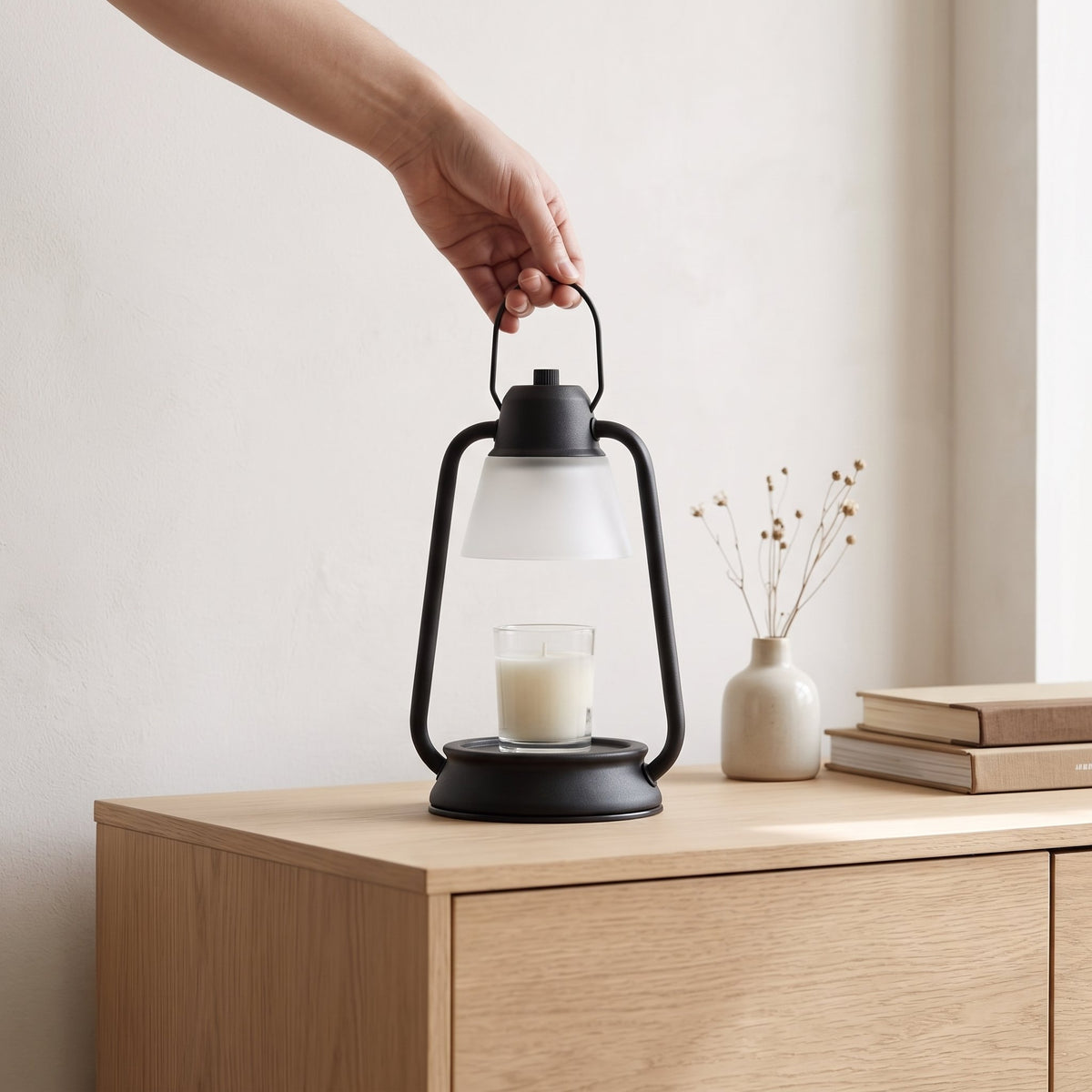 Hand carrying the Embra black lantern candle warmer lamp by its top handle