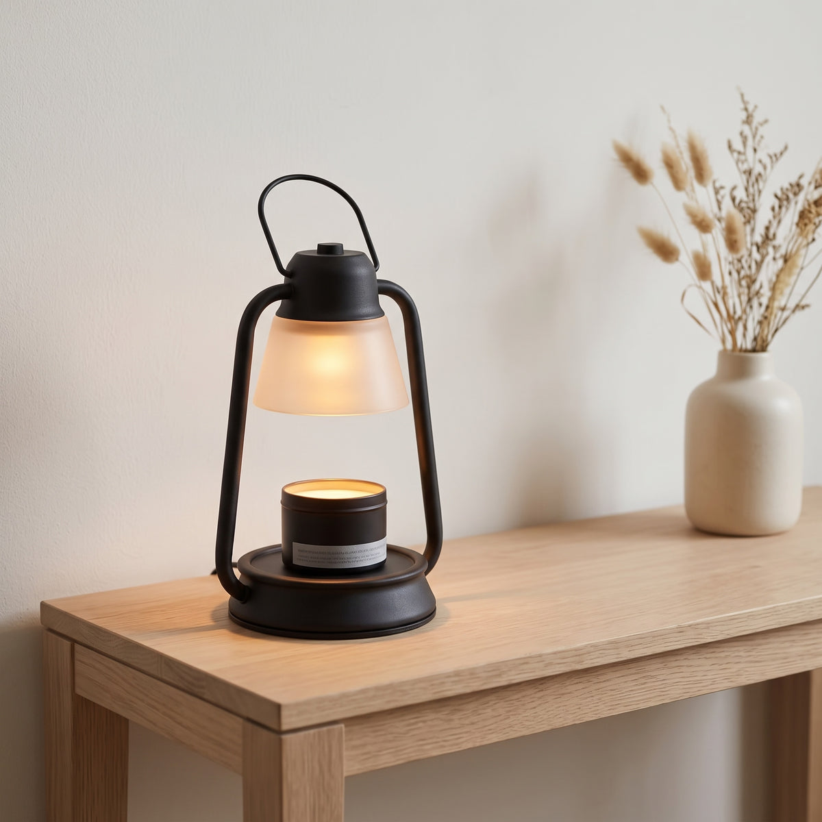 Embra black lantern candle warmer lamp on an oak console table next to a vase of dried grasses
