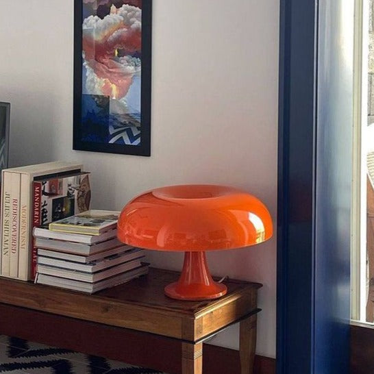 Orange mid-century dome euter table lamp providing a pop of retro colour on a wooden side table in a bright room