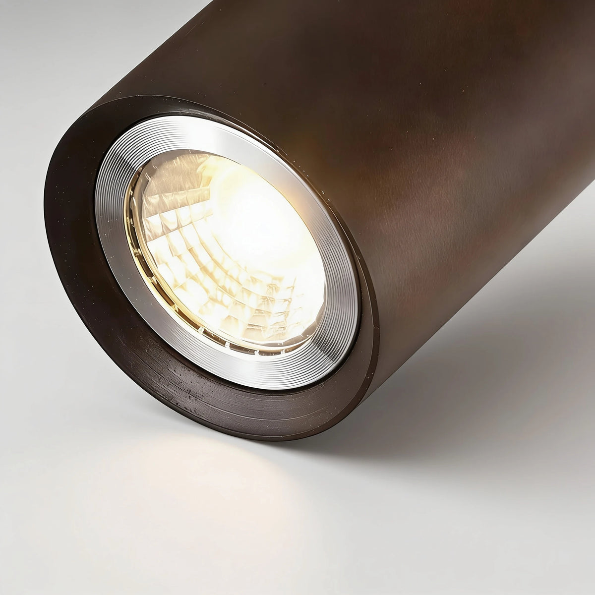 Close-up of a Flar walnut wood spot head with warm LED light glowing from the lens