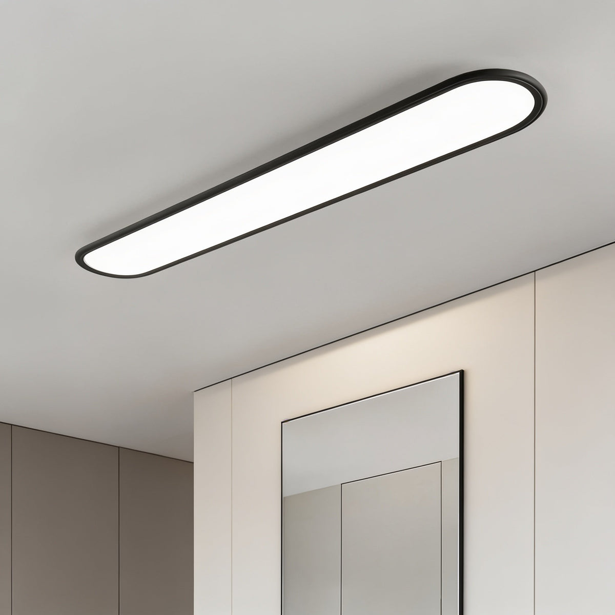 Grale black oval linear LED ceiling light above a mirror and built-in cupboards