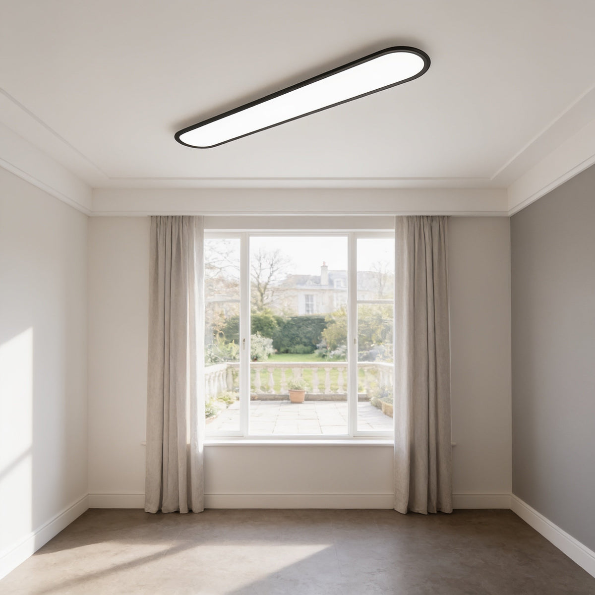 Grale black oval linear LED ceiling light in a bright room with a large window and curtains