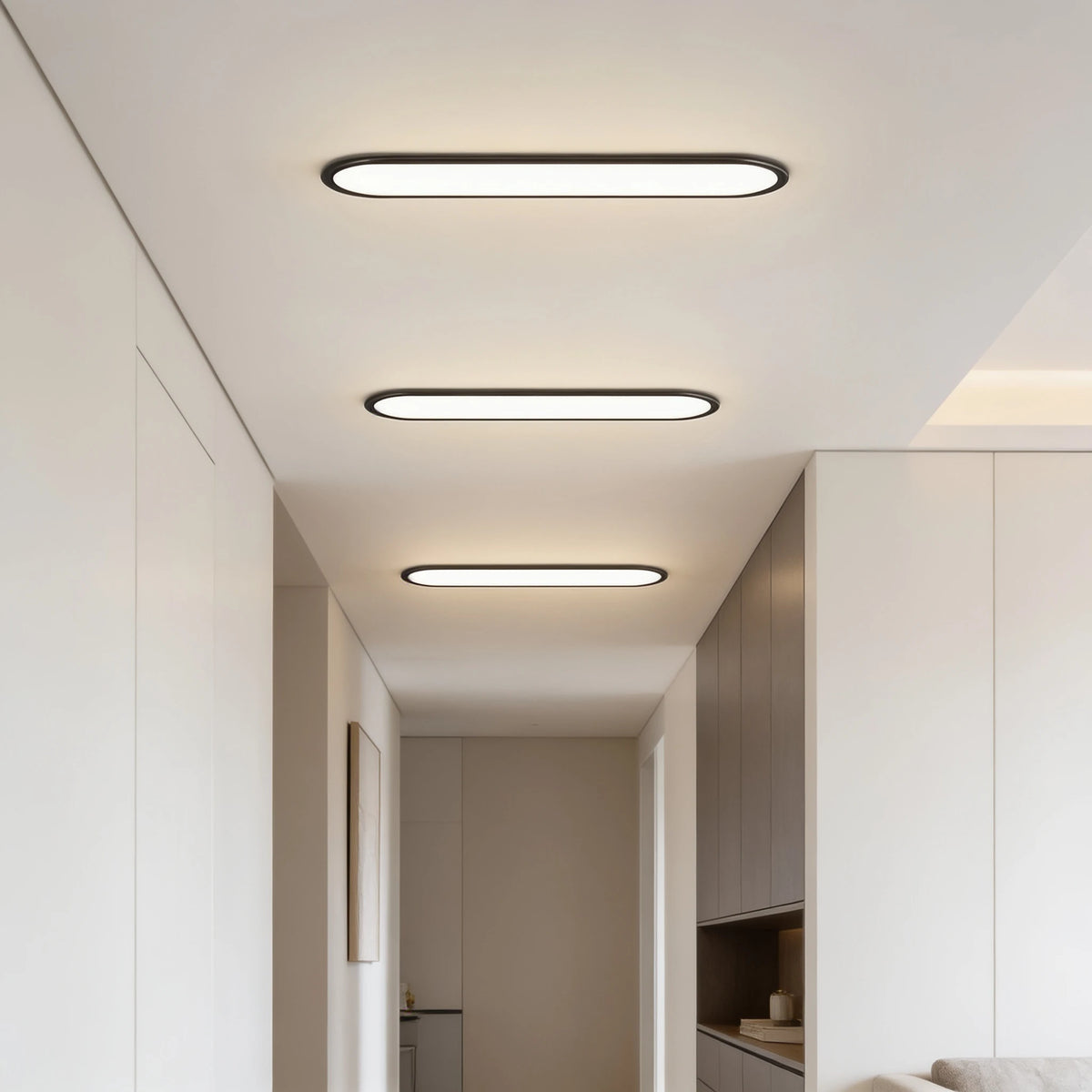 Row of 3 Grale black oval linear LED ceiling lights along a corridor
