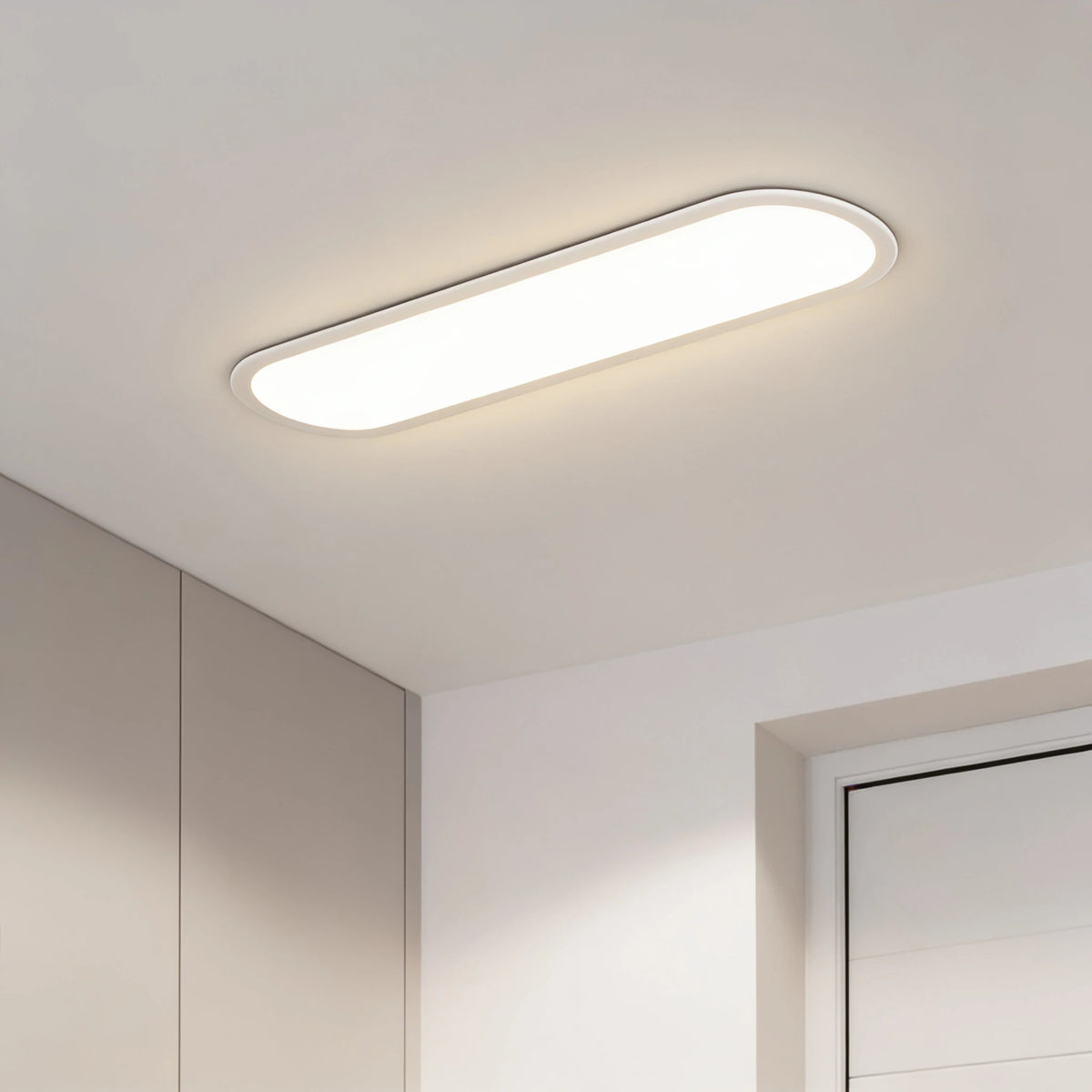 Grale white oval linear LED ceiling light lit above a hallway with cupboards and a door