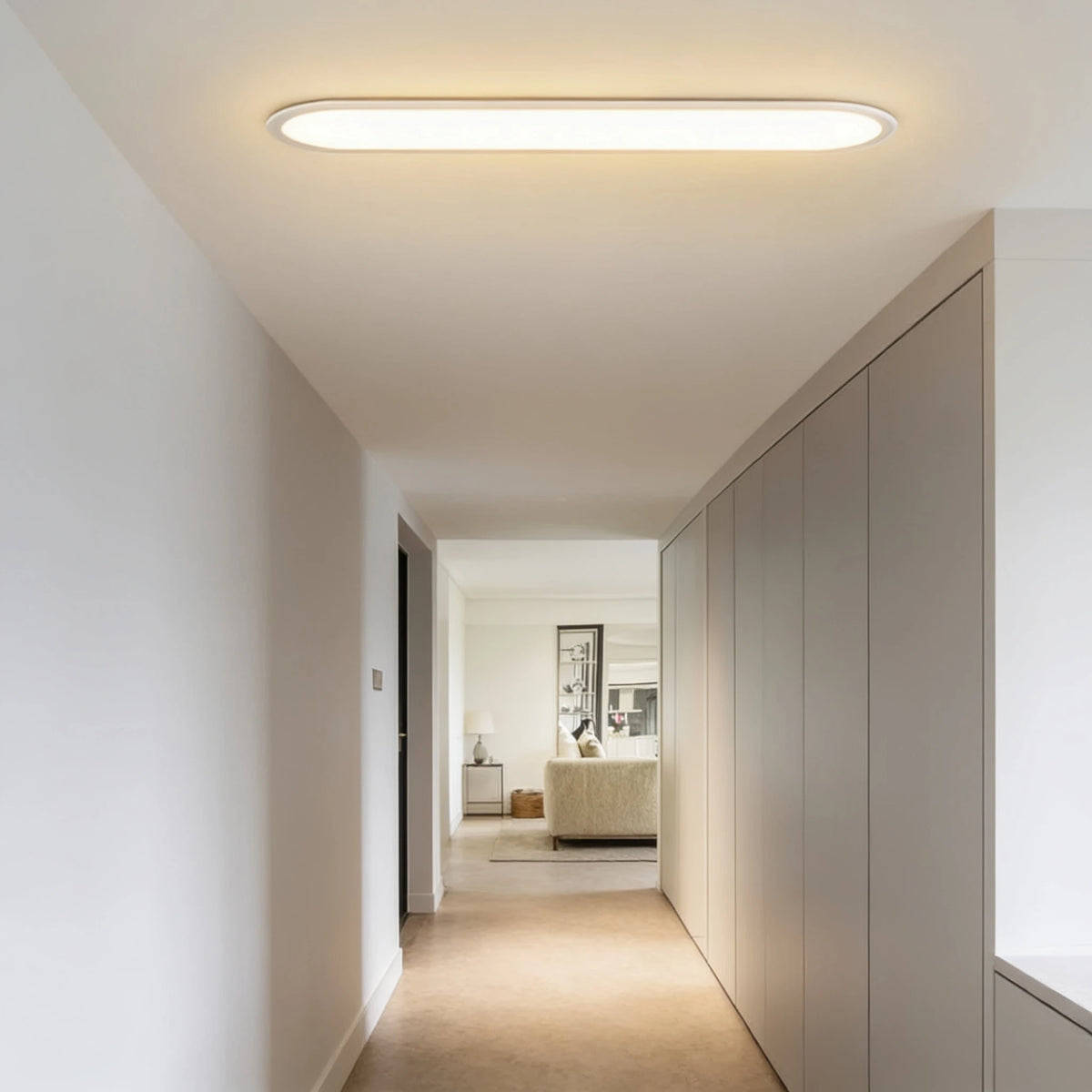 Grale white oval linear LED ceiling light glowing warm white above a long hallway