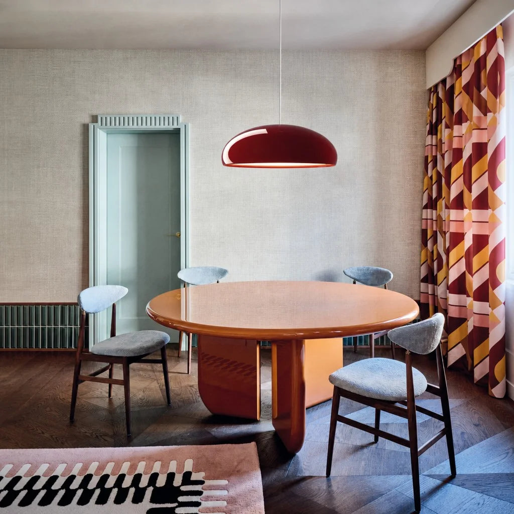 Minimalist red metal huhs pendant light hanging elegantly above a round wooden table