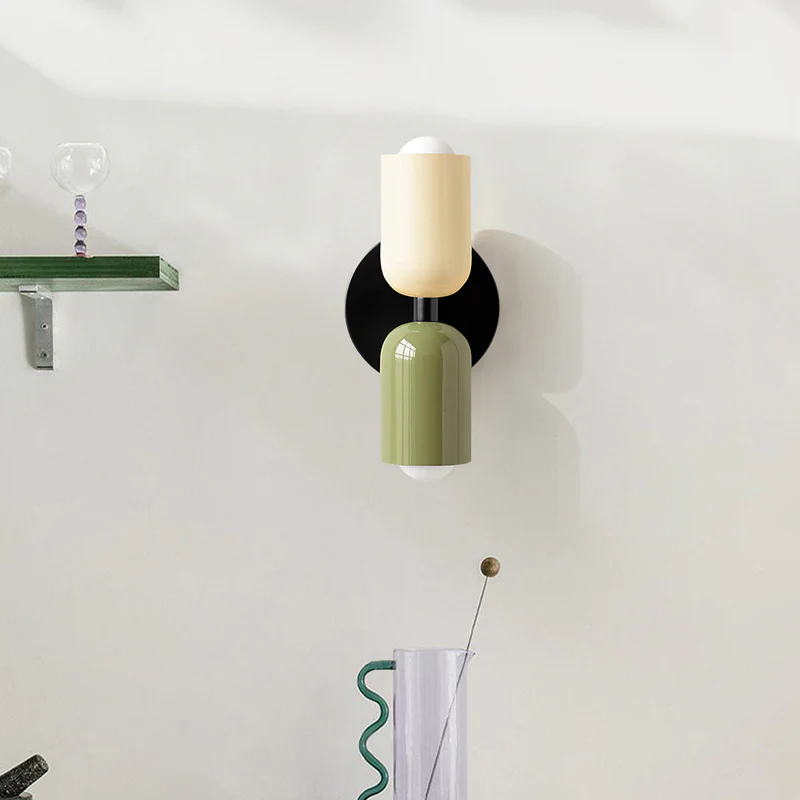 Front view of the hutre beige and green mid-century capsule wall light illuminating a white wall