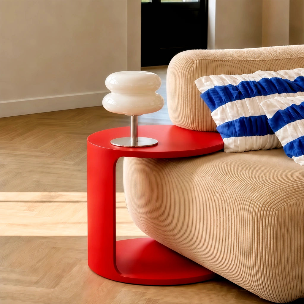 White stacked hutyl glass reading lamp styled on a modern red C-shaped side table next to a sofa